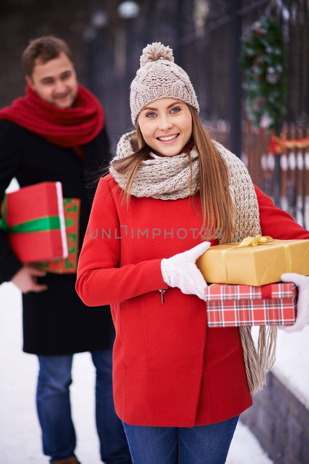 Happy woman with presents looking at camera on background of young man outdoors