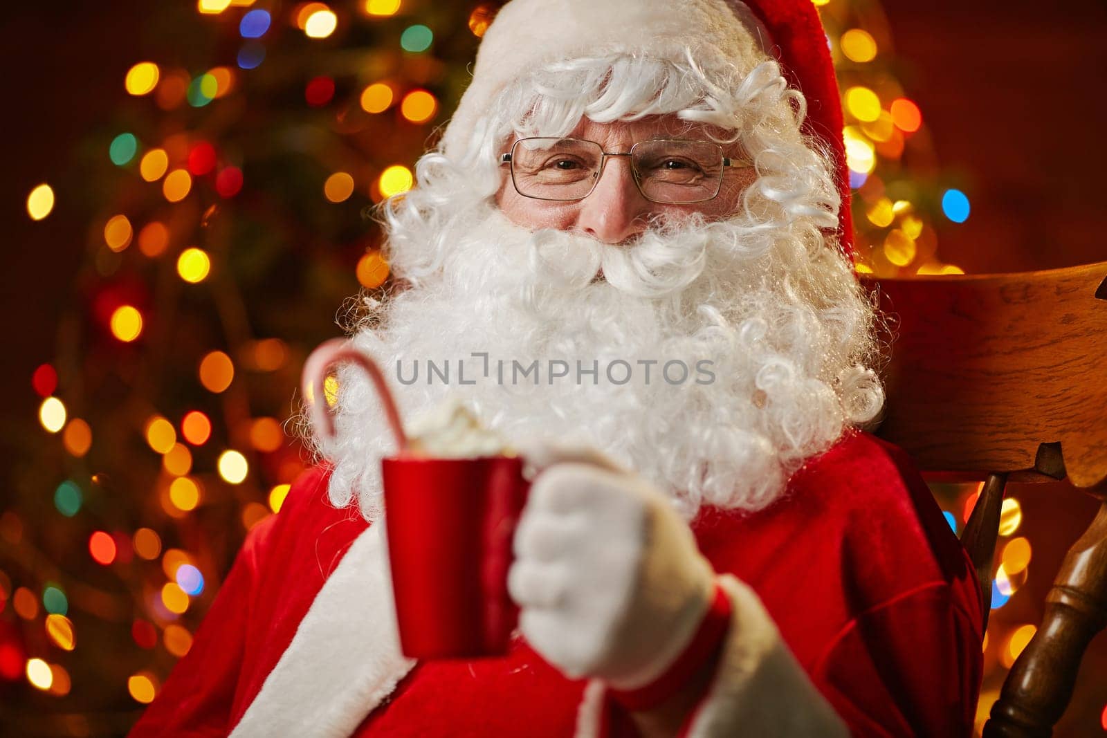 Santa Claus holding red cup with latte and looking at camera