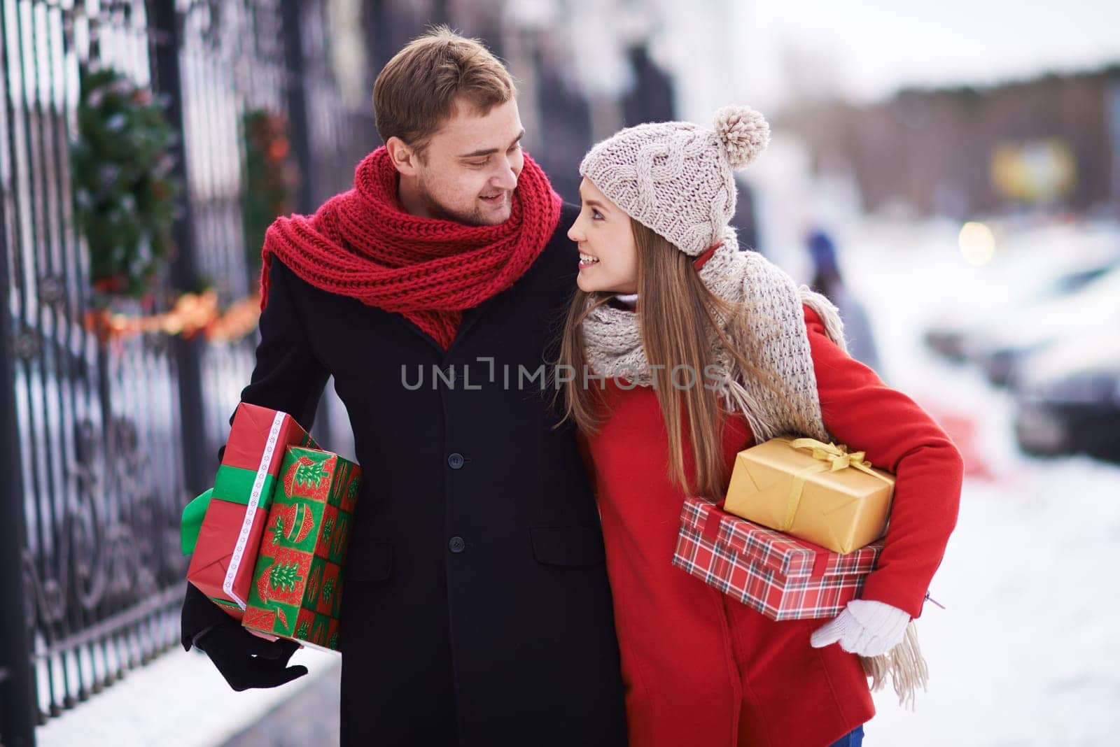 Young couple with giftboxes talking while walking home on Christmas eve