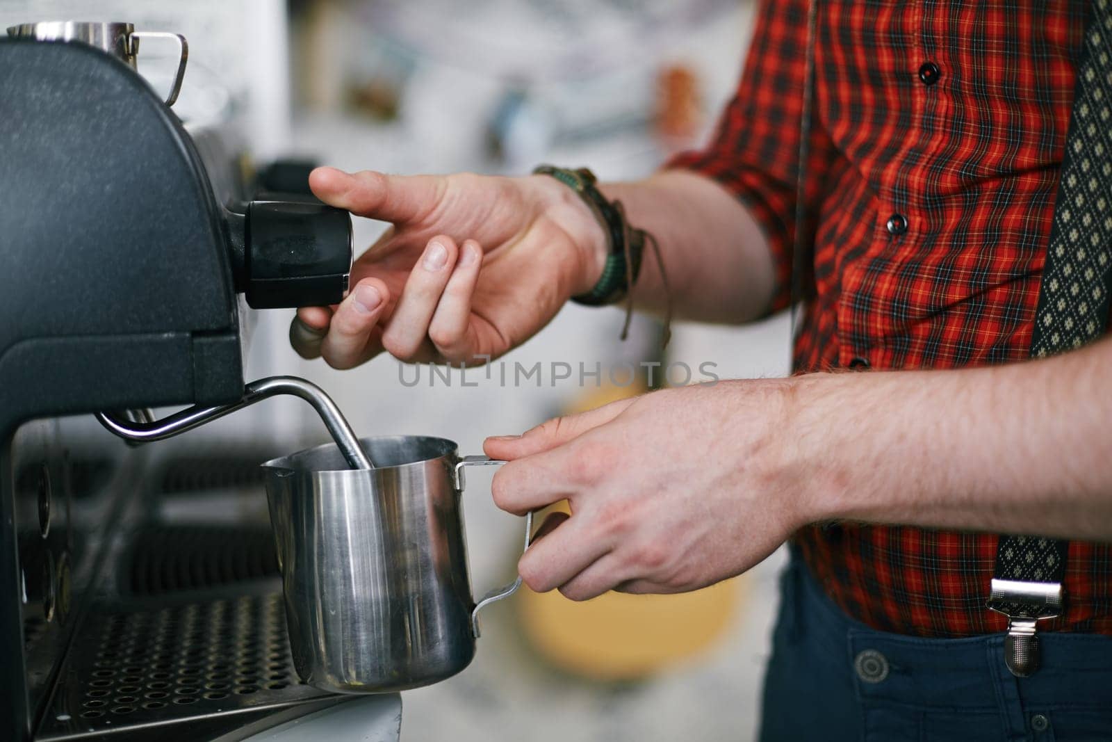 Barista holding metallic mug while using coffee machine
