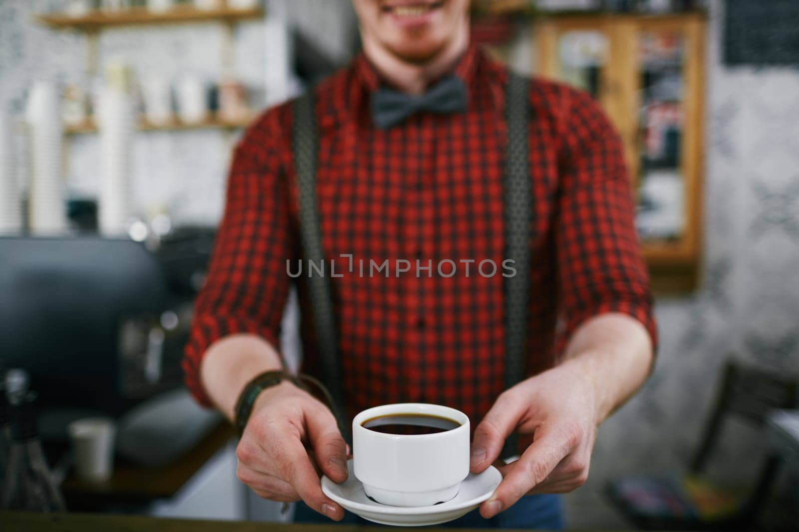 Barista holding cup of black coffee on saucer