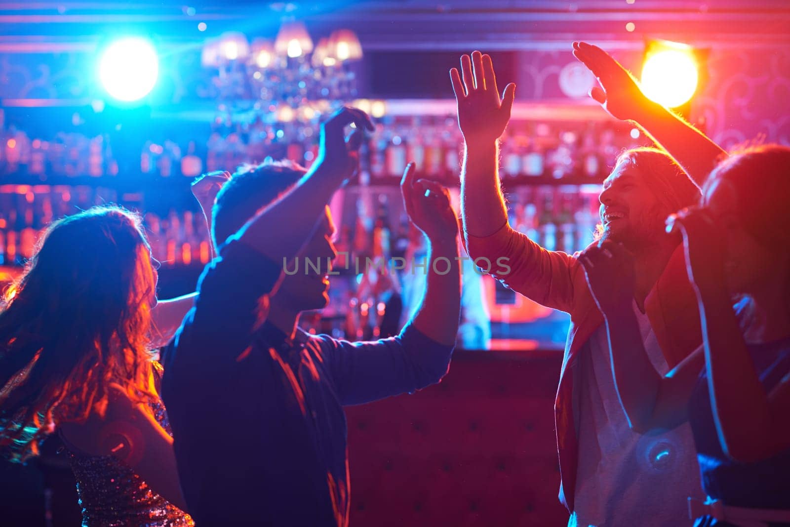 Happy friends dancing at party in bar