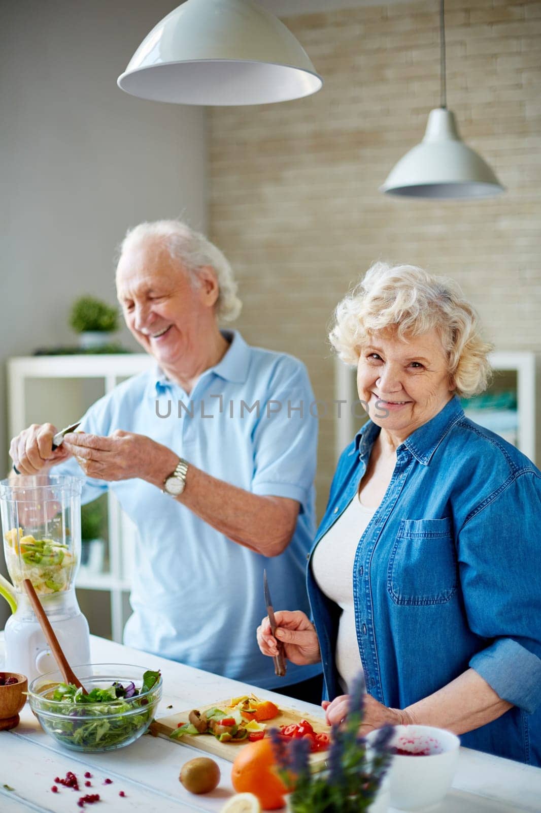 Happy seniors cooking vegetarian food in the kitchen