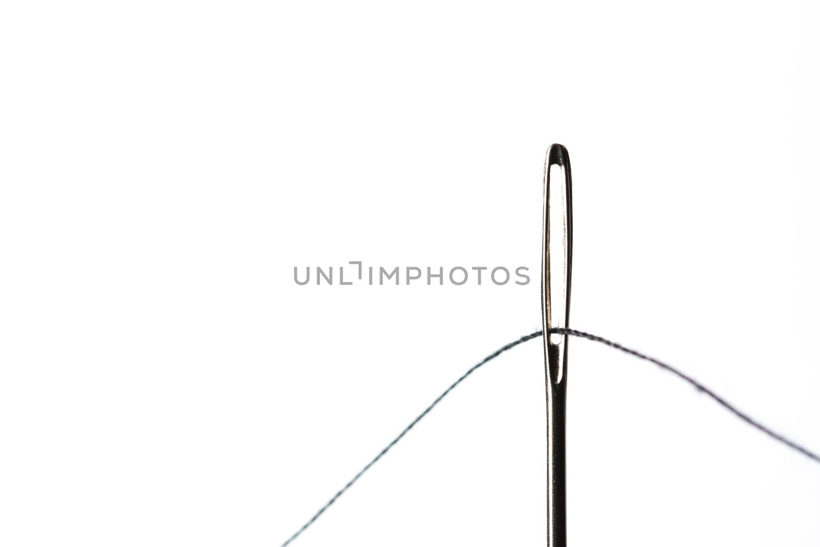 Sewing Needle Close Up With Black Thread through the eye.