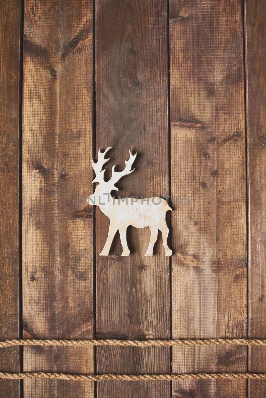 Toy reindeer over two ropes on wooden background