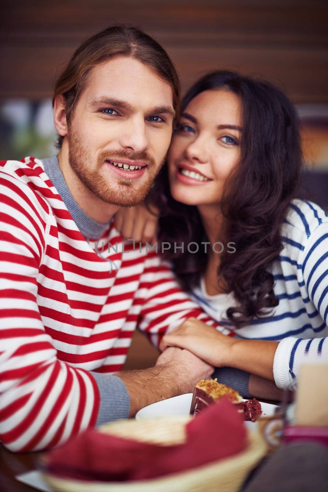 Affectionate dates looking at camera while sitting in cafe