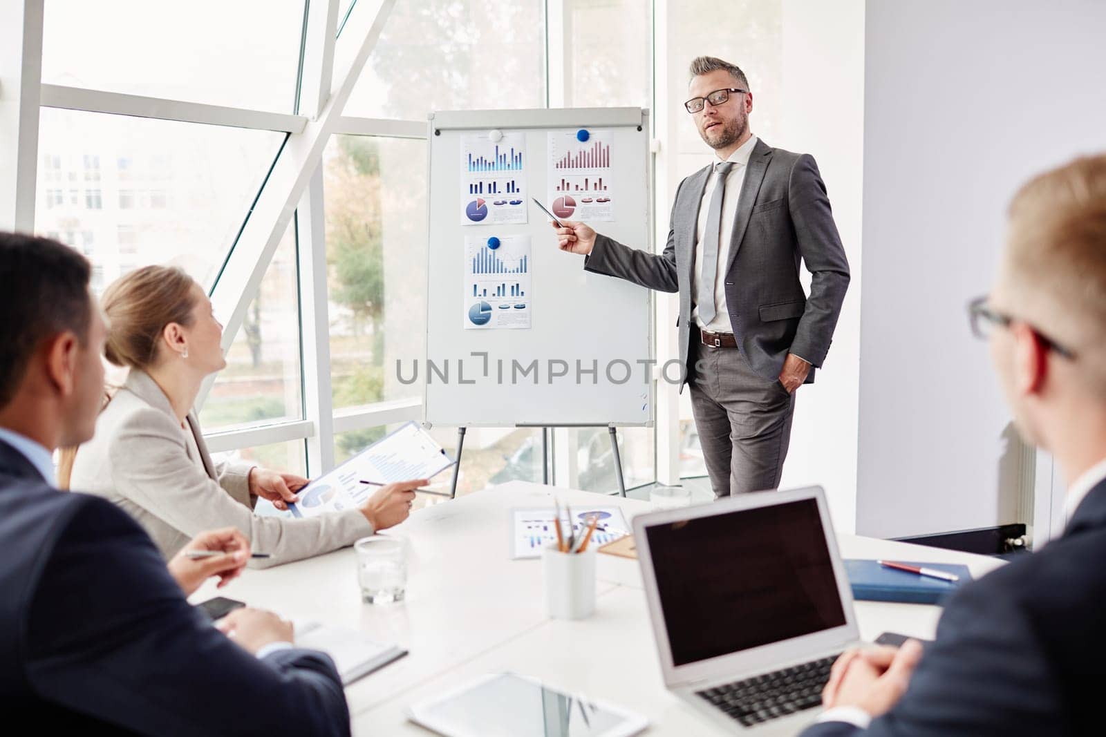 Experienced businessman by whiteboard looking at camera while presenting his review of financial analysis
