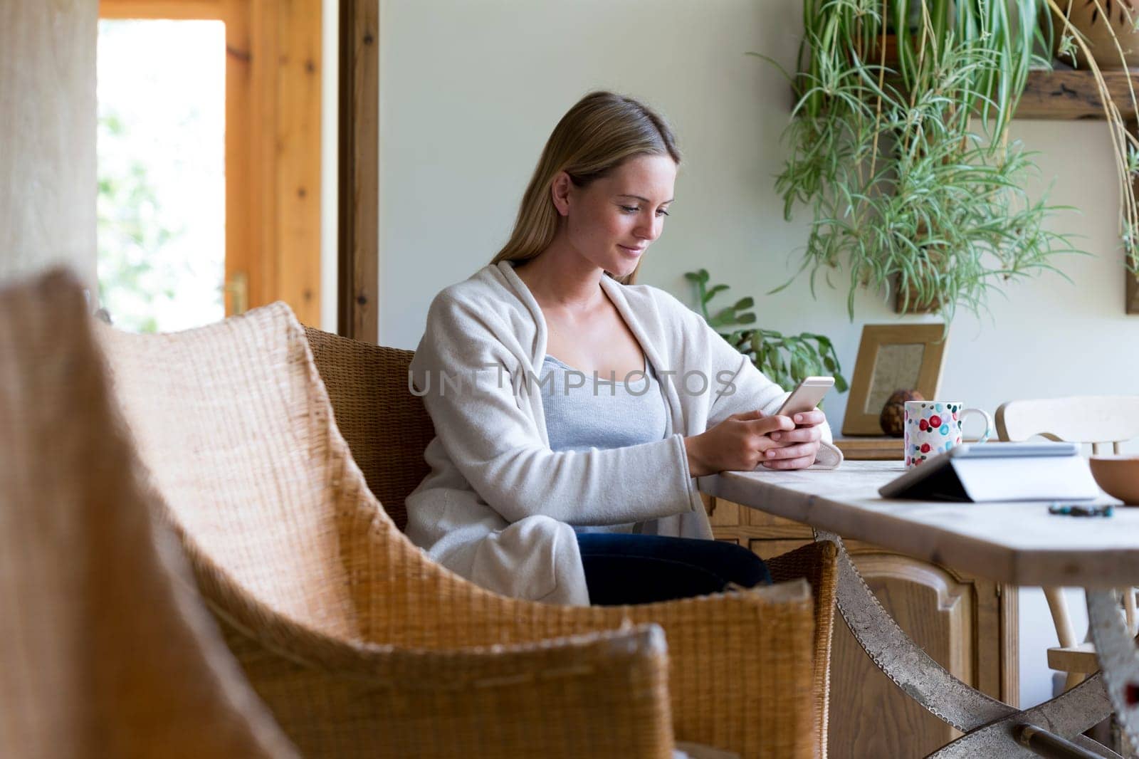 Woman sitting at a table in her home using a smartphone