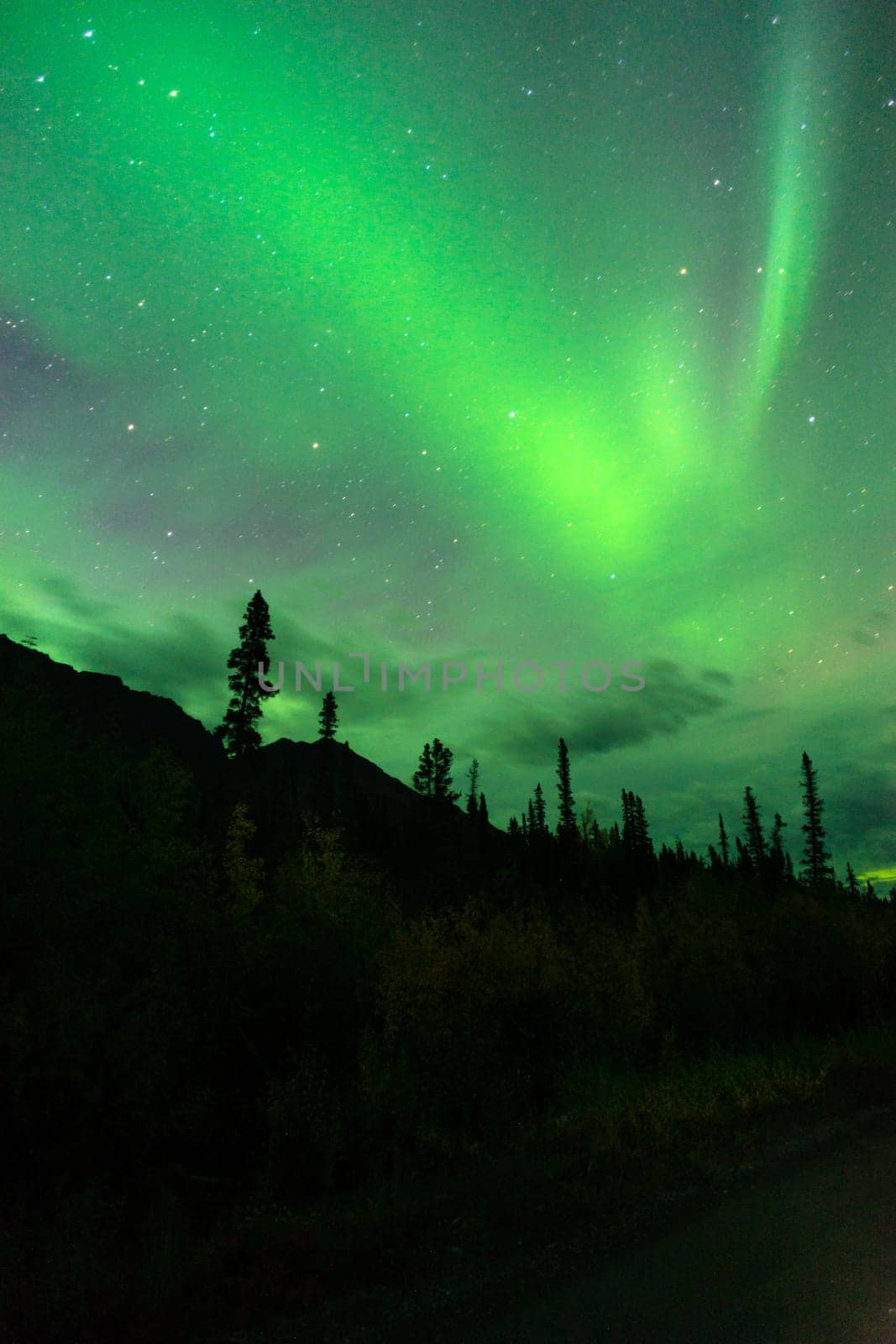 The Northern Lights emerge through the clouds in remote Alaska