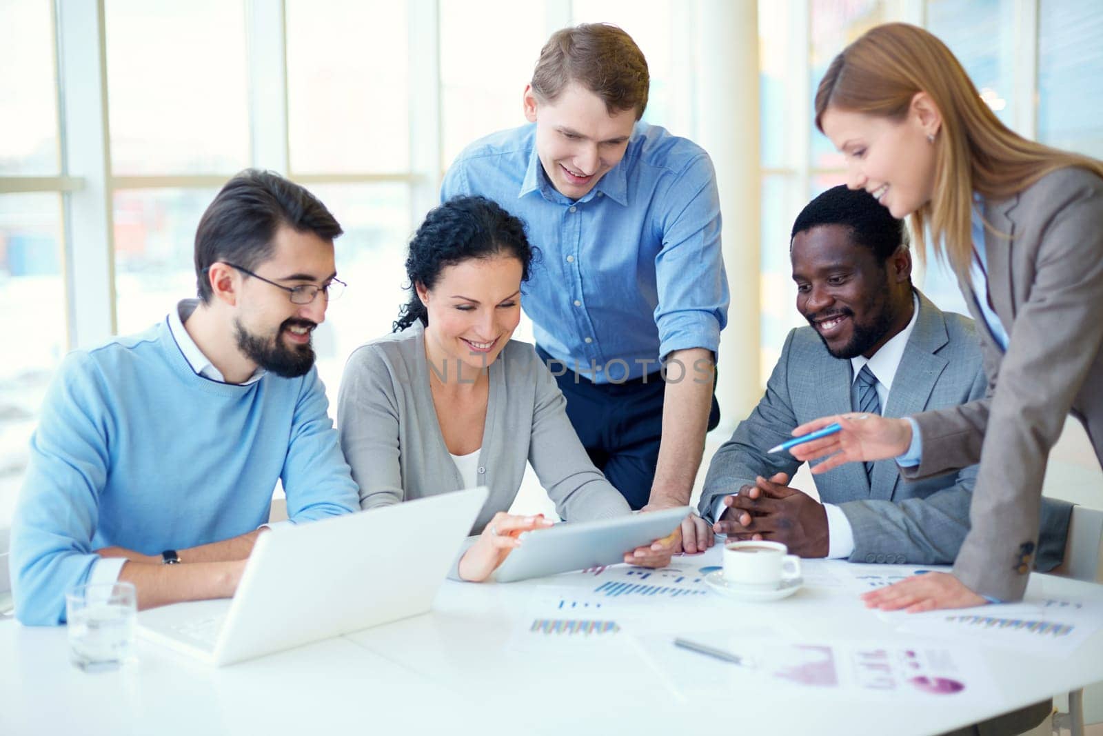 Group of employees studying and discussing electronic data at meeting