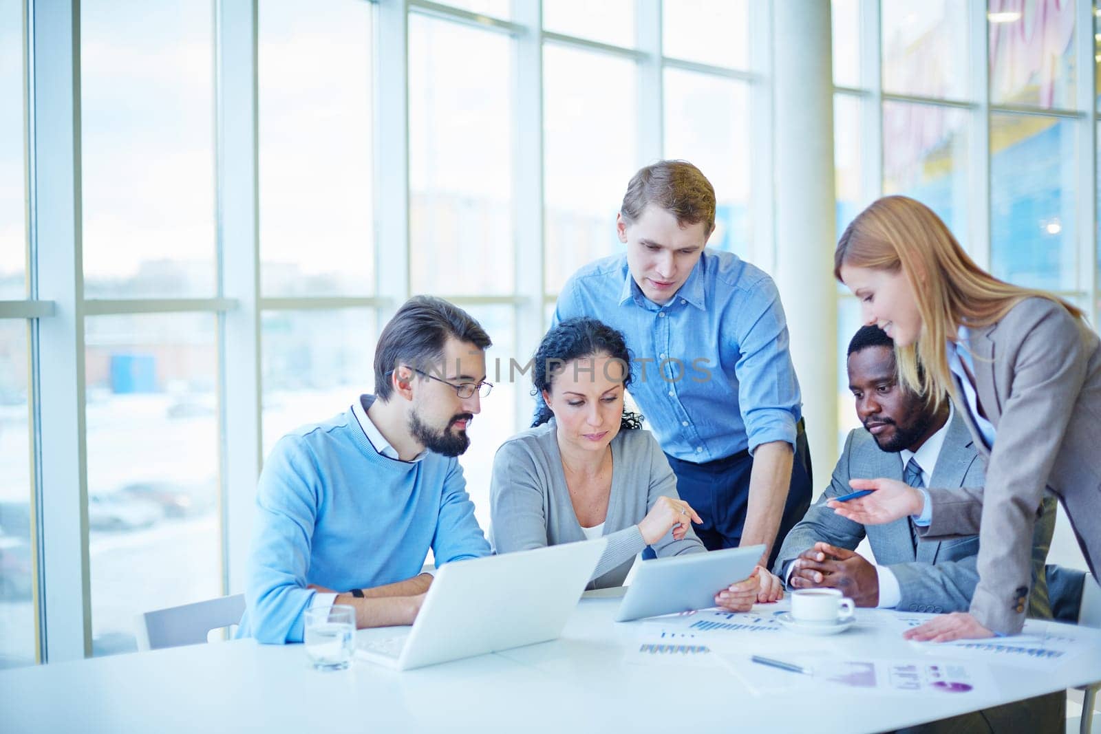 Group of employees consulting electronic data while making analysis