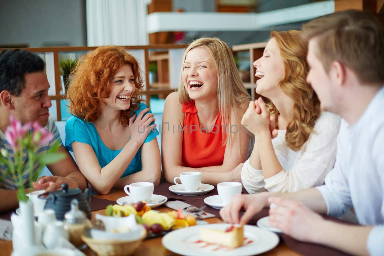 Happy girls laughing with their boyfriends near by while sitting in cafe