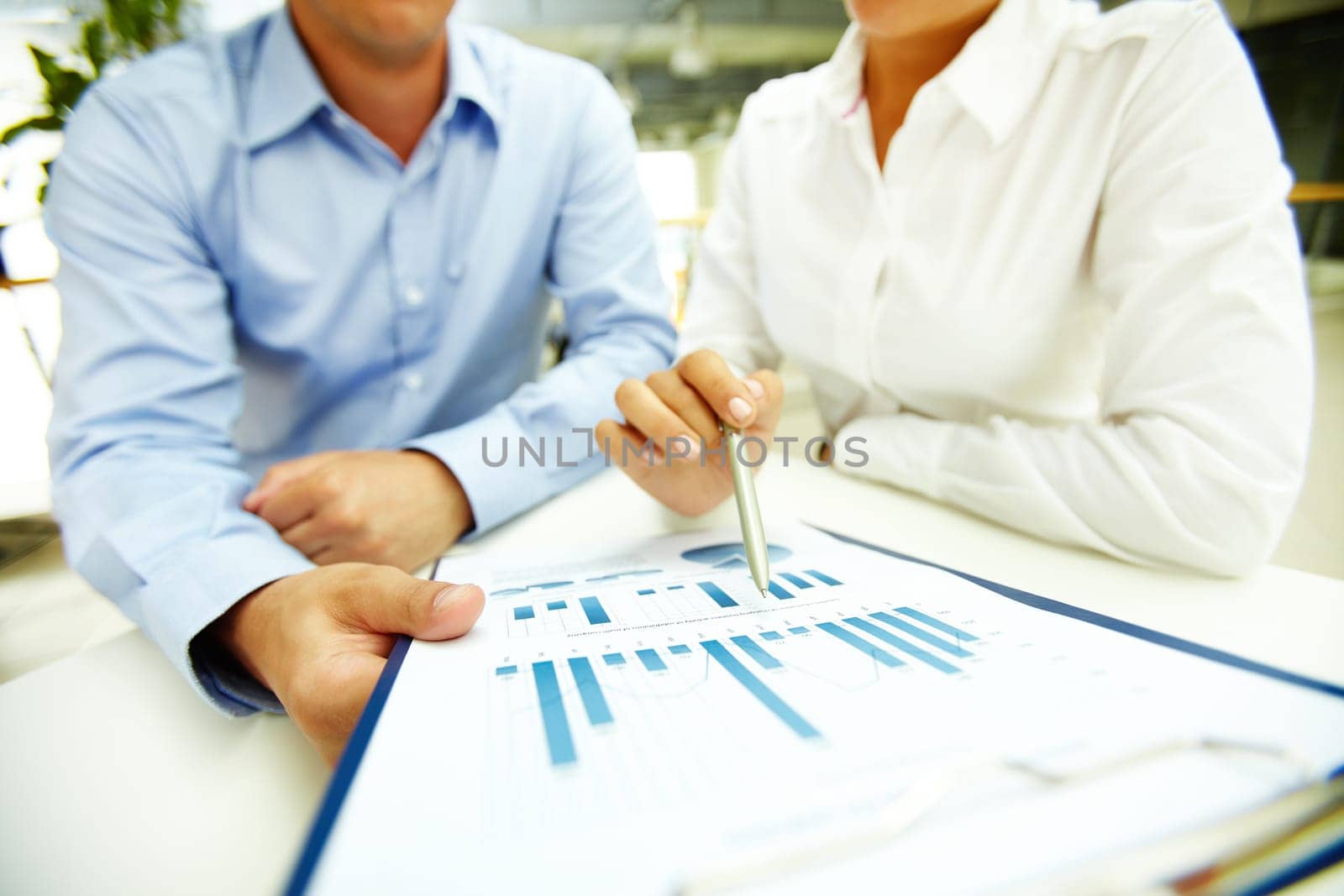 Businesswoman with pen explaining data to colleague