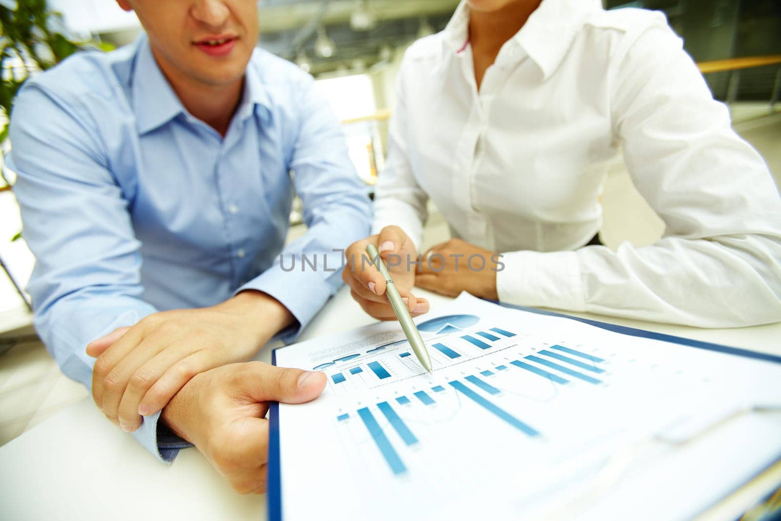 Businesswoman pointing at chart in document held by her colleague