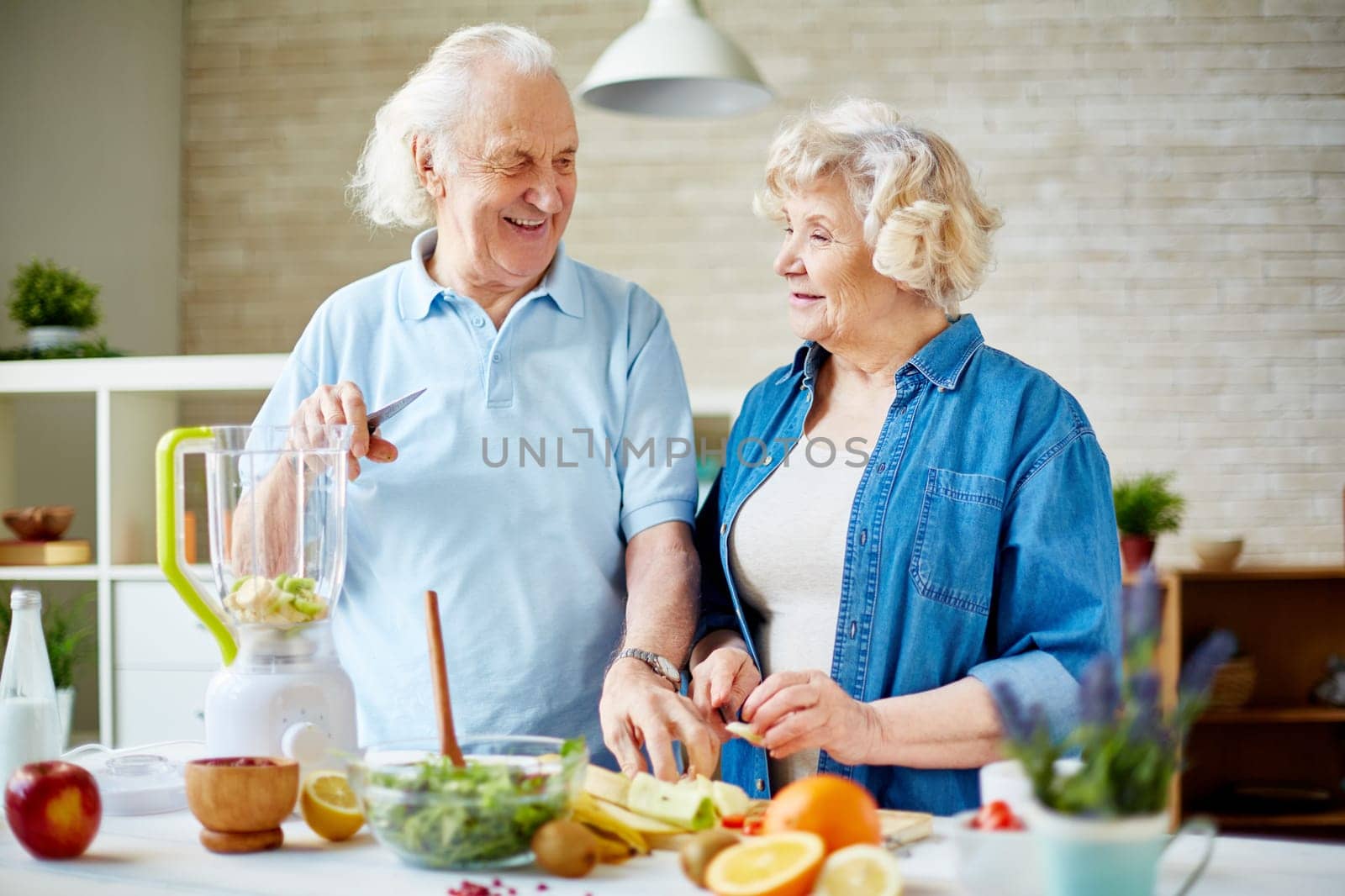 Senior husband and wife preparing fruit smoothie