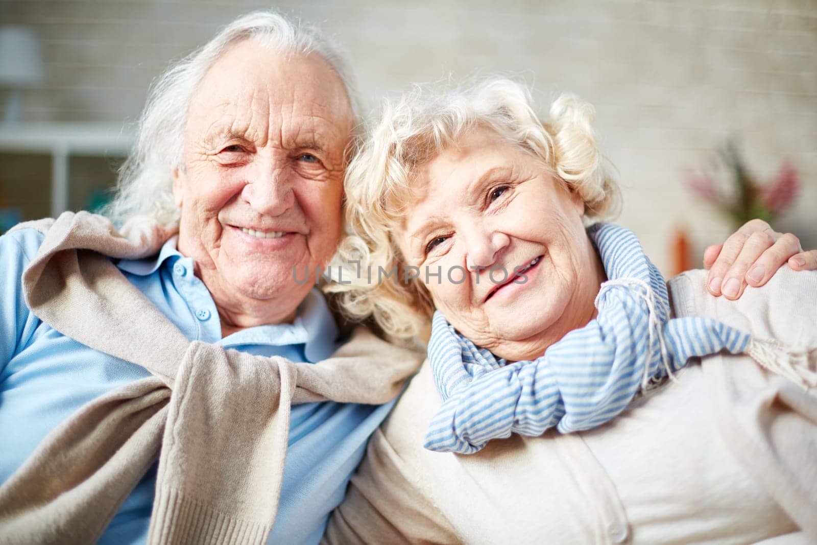 Affectionate elderly couple looking at camera with smiles