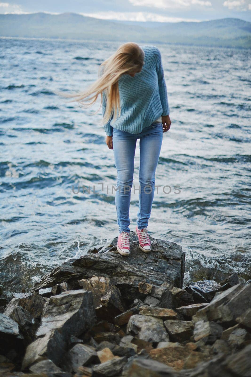Young woman in jeans and pullover spending weekend by the seaside