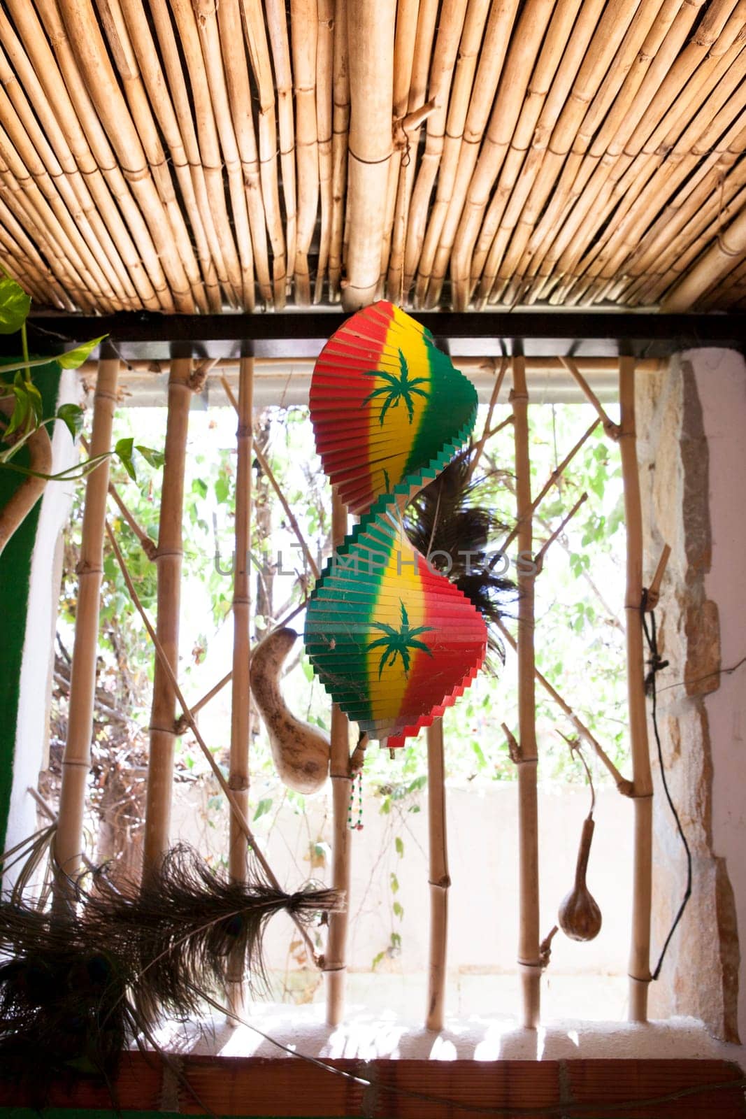 Hanging wooden spiral decorative craft with reggae color over open window of a tropical hut