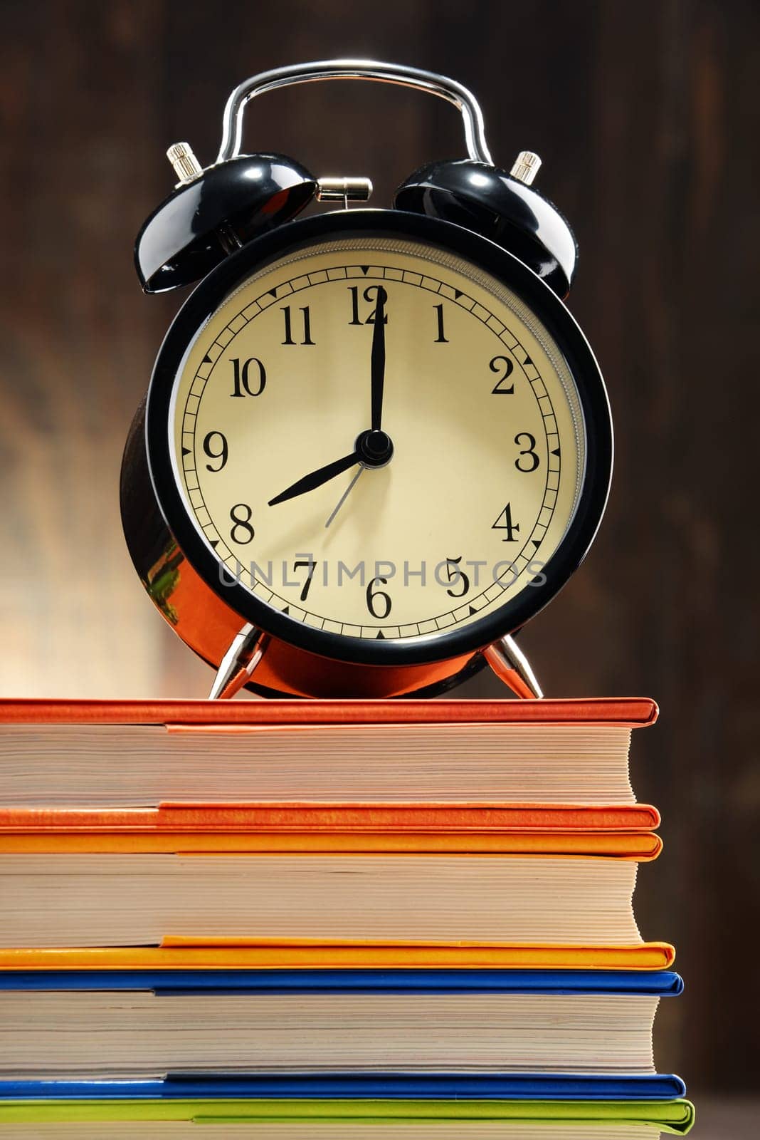 Composition with old black alarm clock on the stack of books.