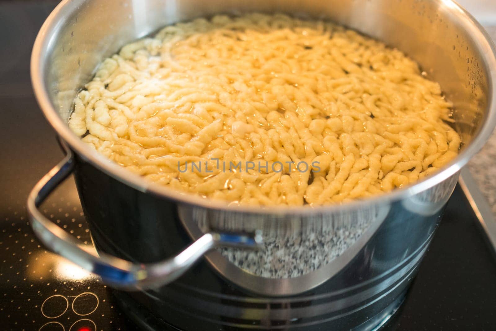 Spätzle in the water in a cooking pot on a stove