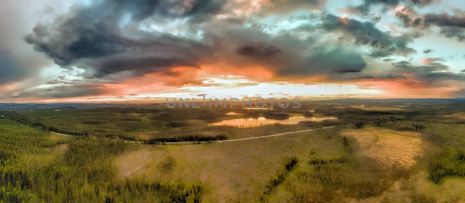 Huge storms colored by sunset above the forests in Sweden, aerial panorama