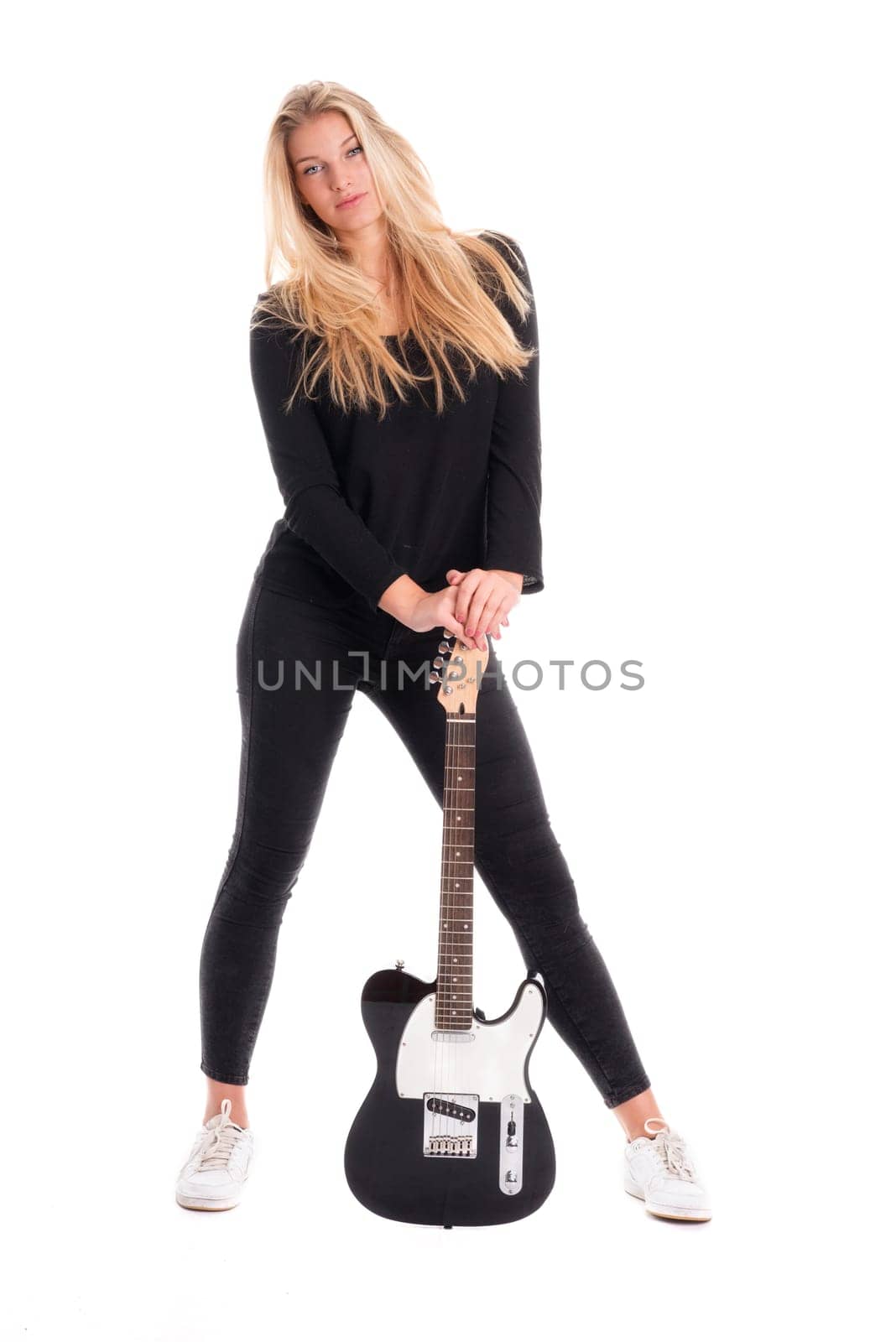Girl with erotic charisma stands in front of an electric guitar
