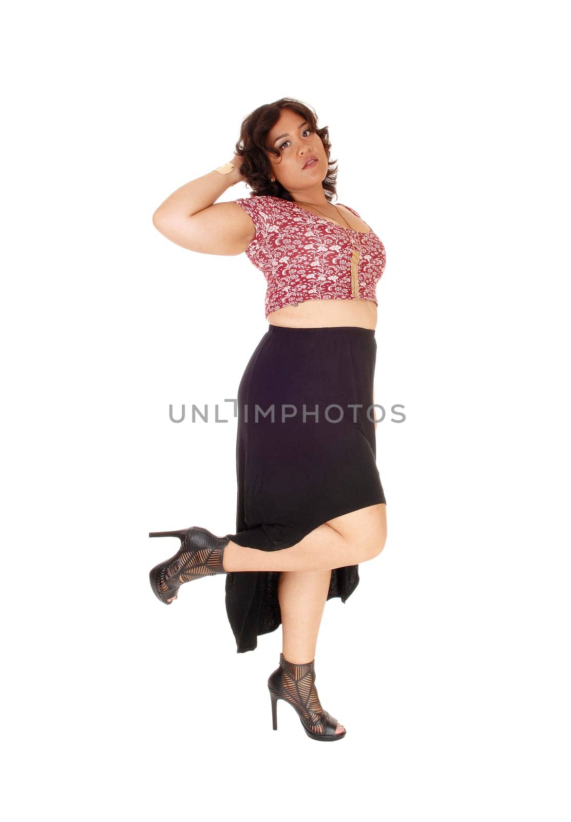 A mixed raced young woman standing isolated for white background.in a black skirt, lifting up one leg..