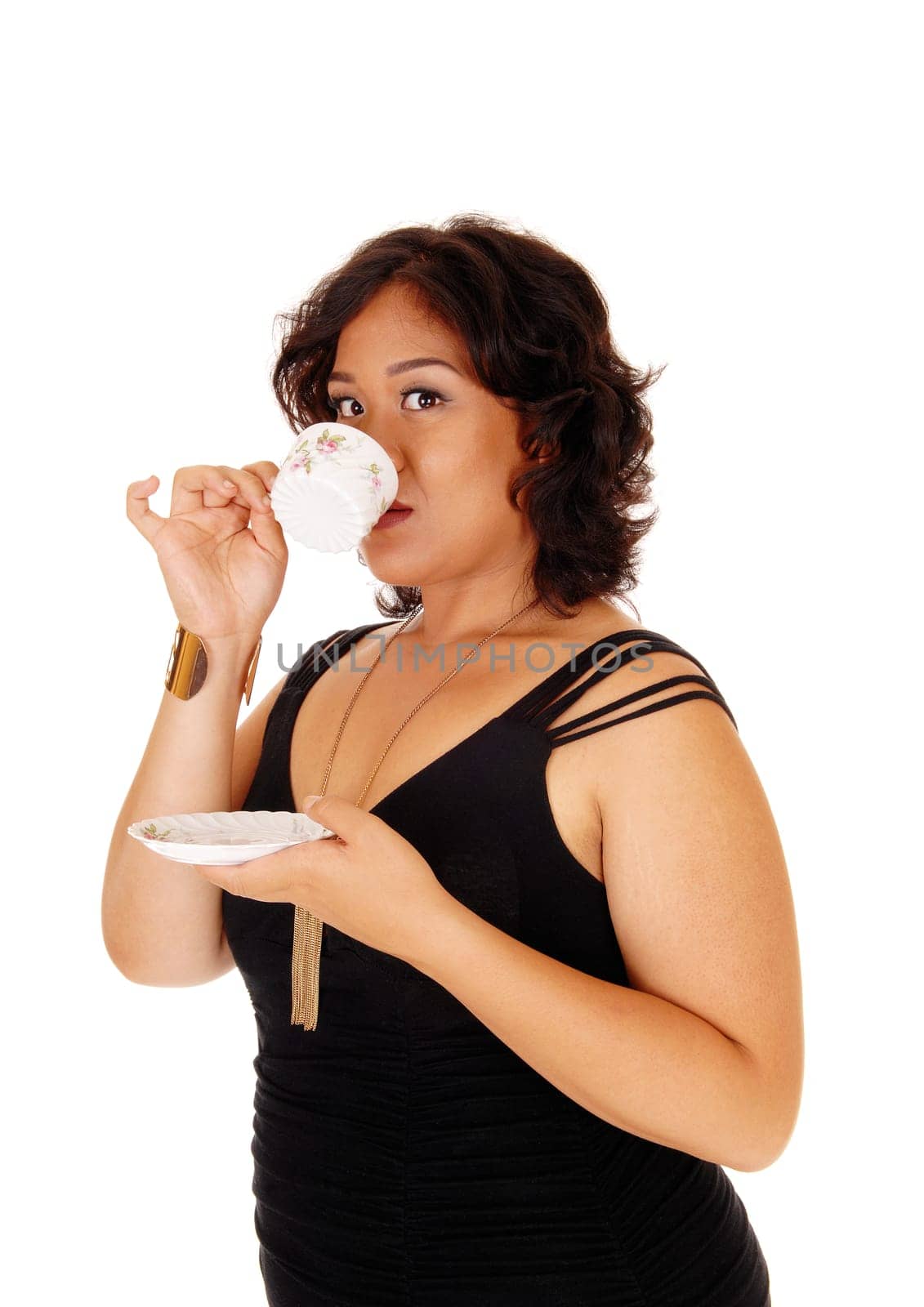 A young plus size pretty woman drinking a cup of coffee, holding the.saucer in her hand, isolated for white background..