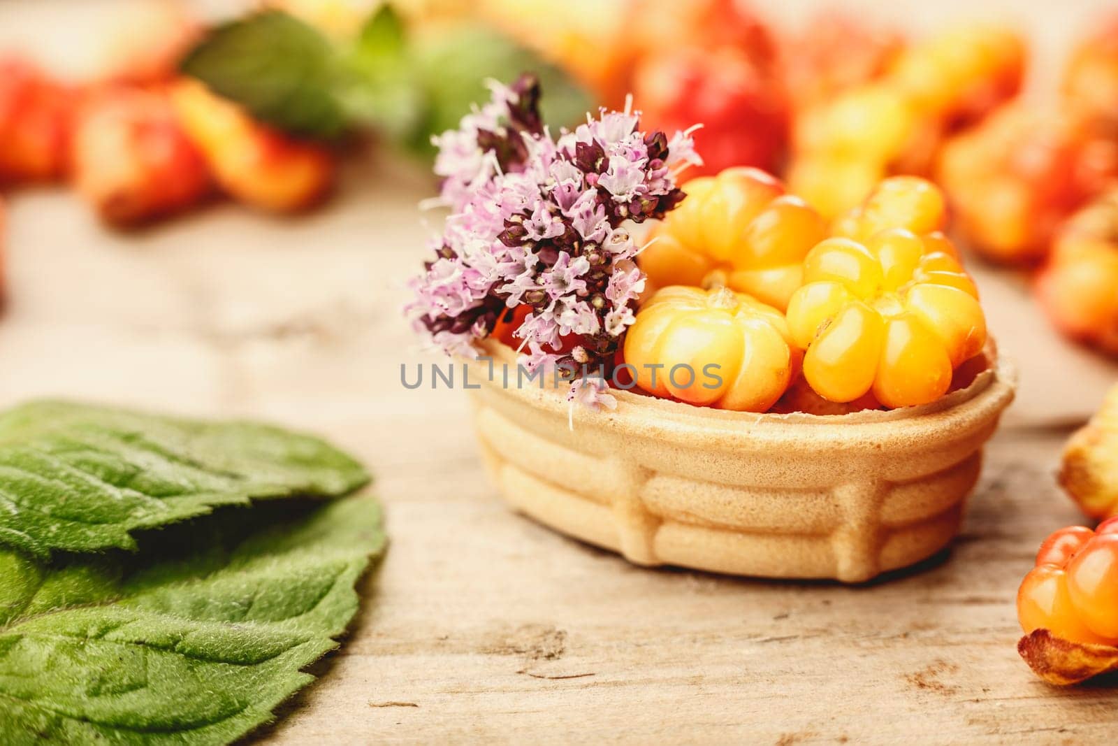 Cloudberry tart decorated with wild marjoram. Sweet baked dessert with fresh wild cloudberries on a wooden table. Instagram filter styled