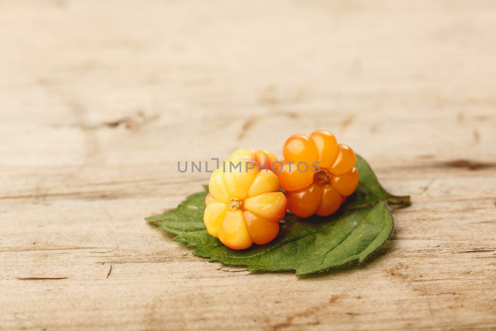 Cloudberries (moroshka) on a wooden table. Wild northern berry. Shallow depth of field
