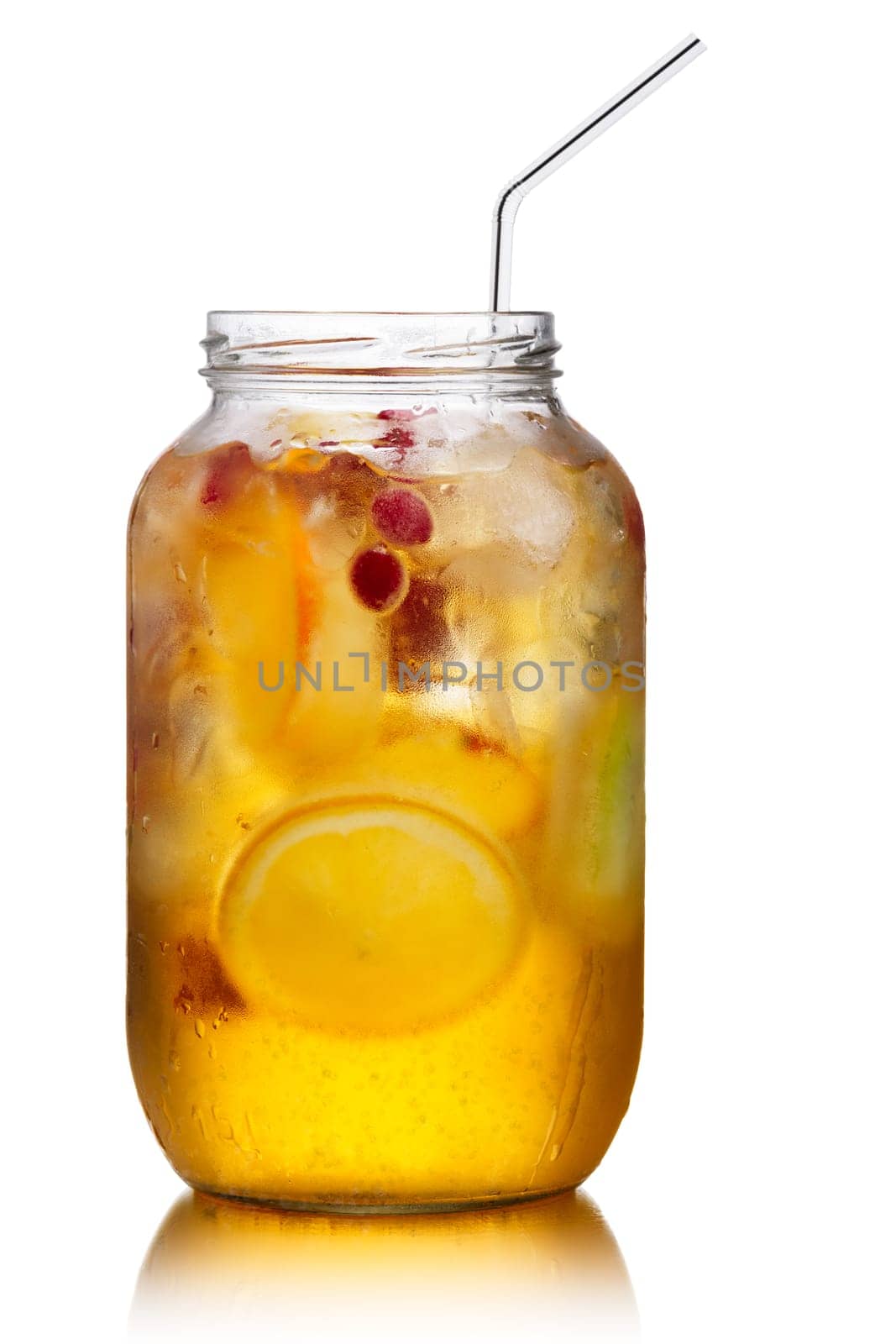 Glass jar of homemade spritzer (schorle) with carbonated apple juice served with frozen fruit wheels, ice cubes and wild cranberry