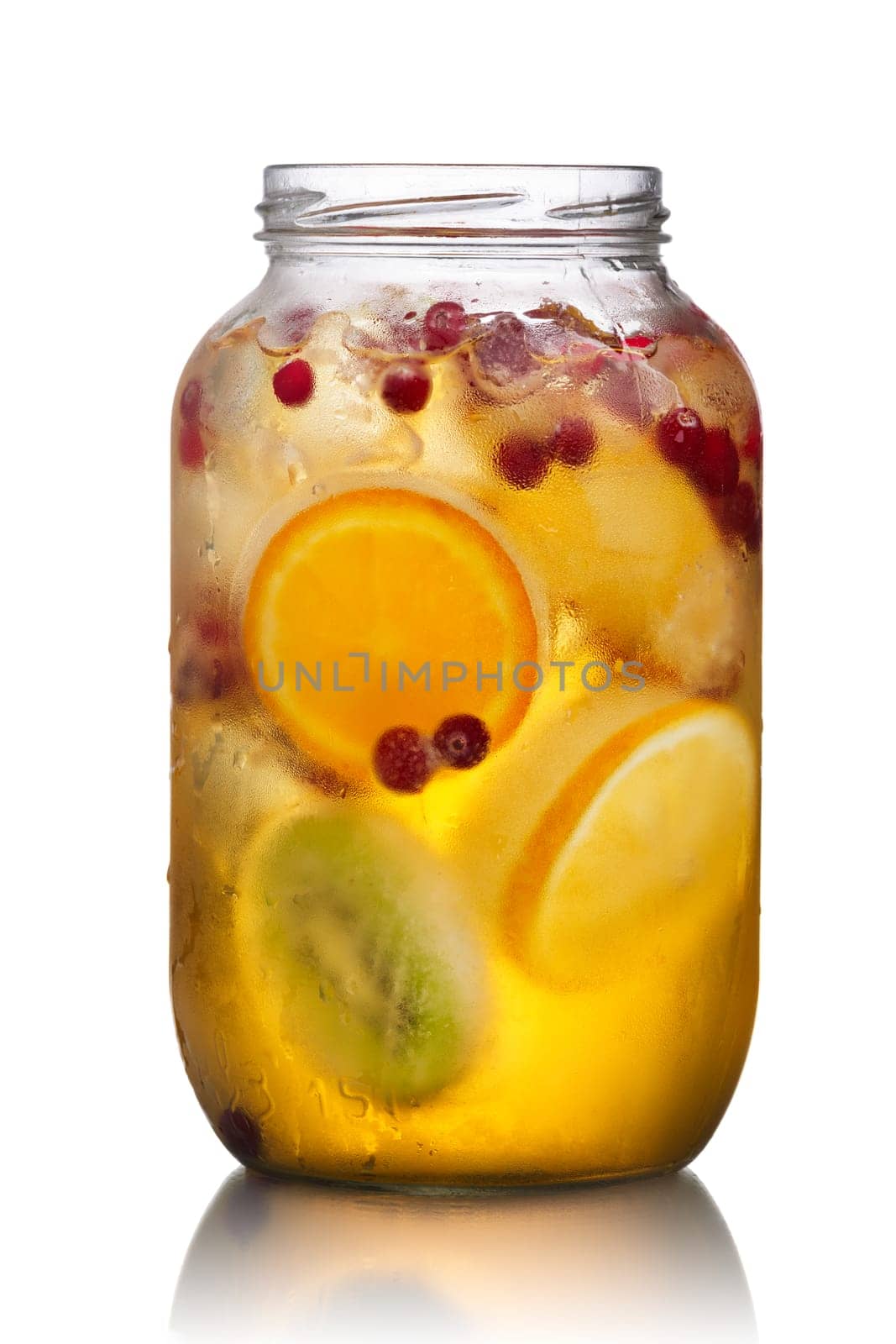 Glass jar of homemade spritzer (schorle) with carbonated apple juice served with frozen fruit wheels, ice cubes and wild cranberry