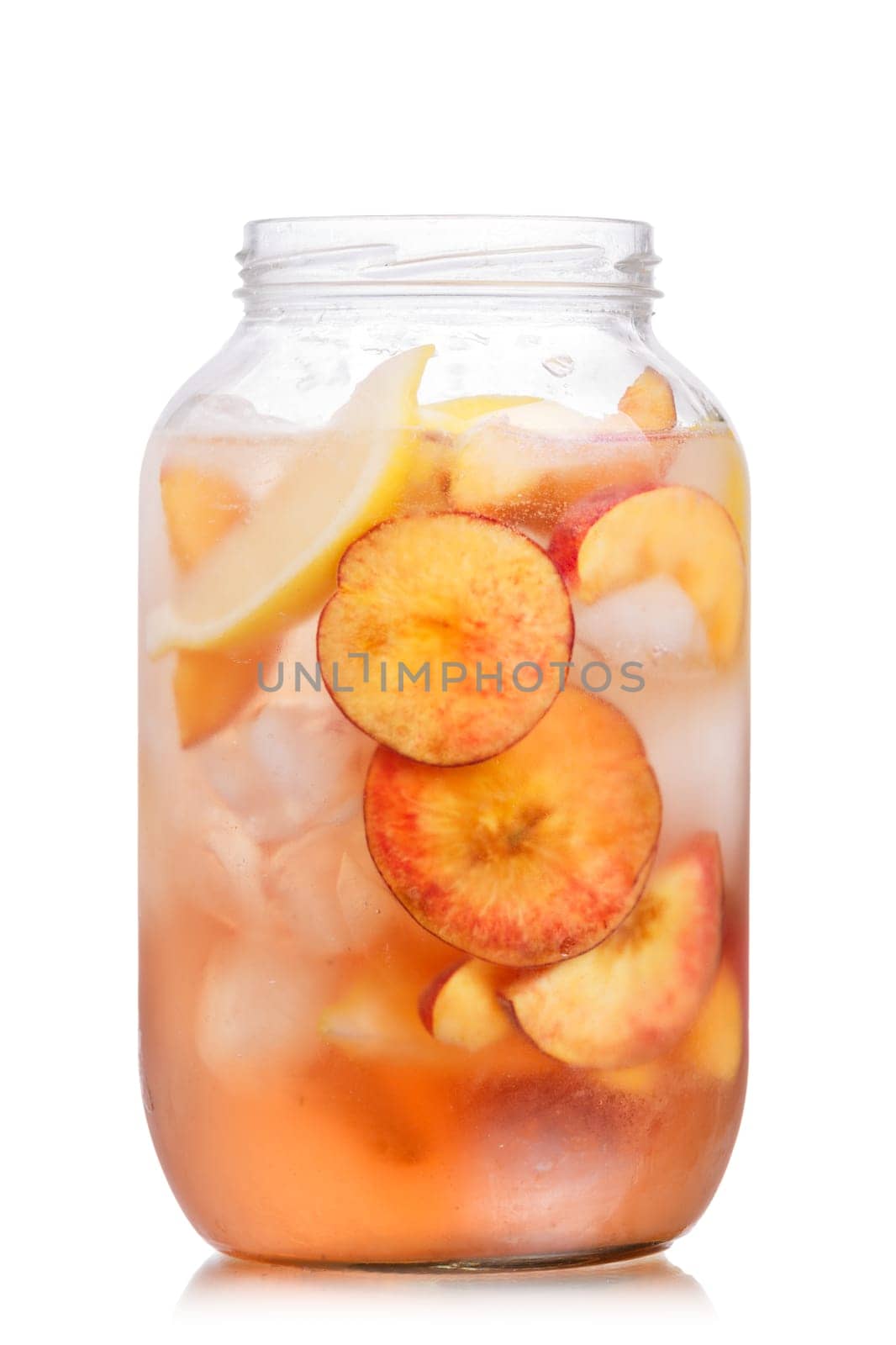 Jar of carbonated peach lemonade garnished with peach wheel and lemon slice. Glass jar full of cold peach spritzer with peach and lemon slices.