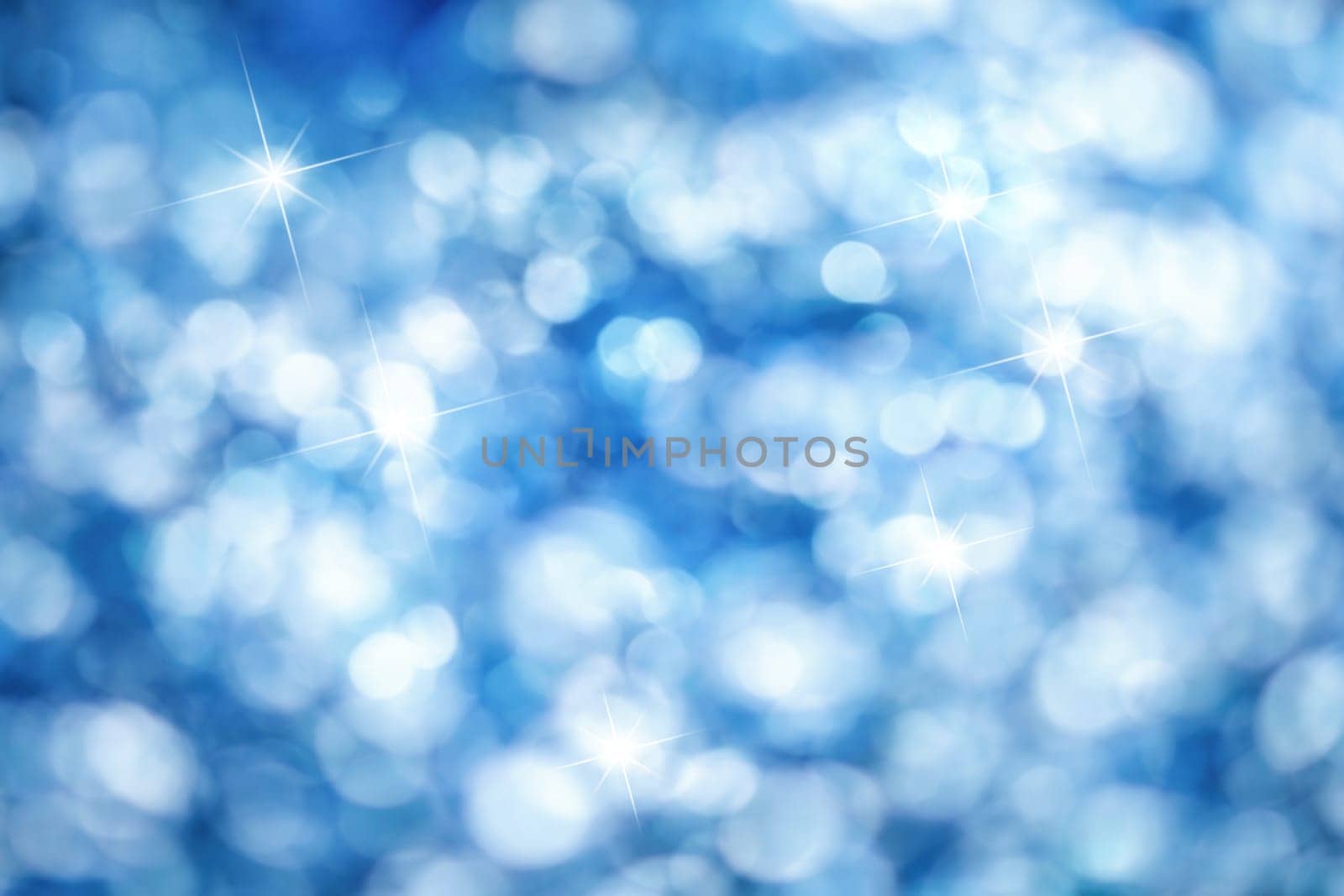 Out of focus lights creating a blue bokeh background with bright highlights,ideal for Christmas