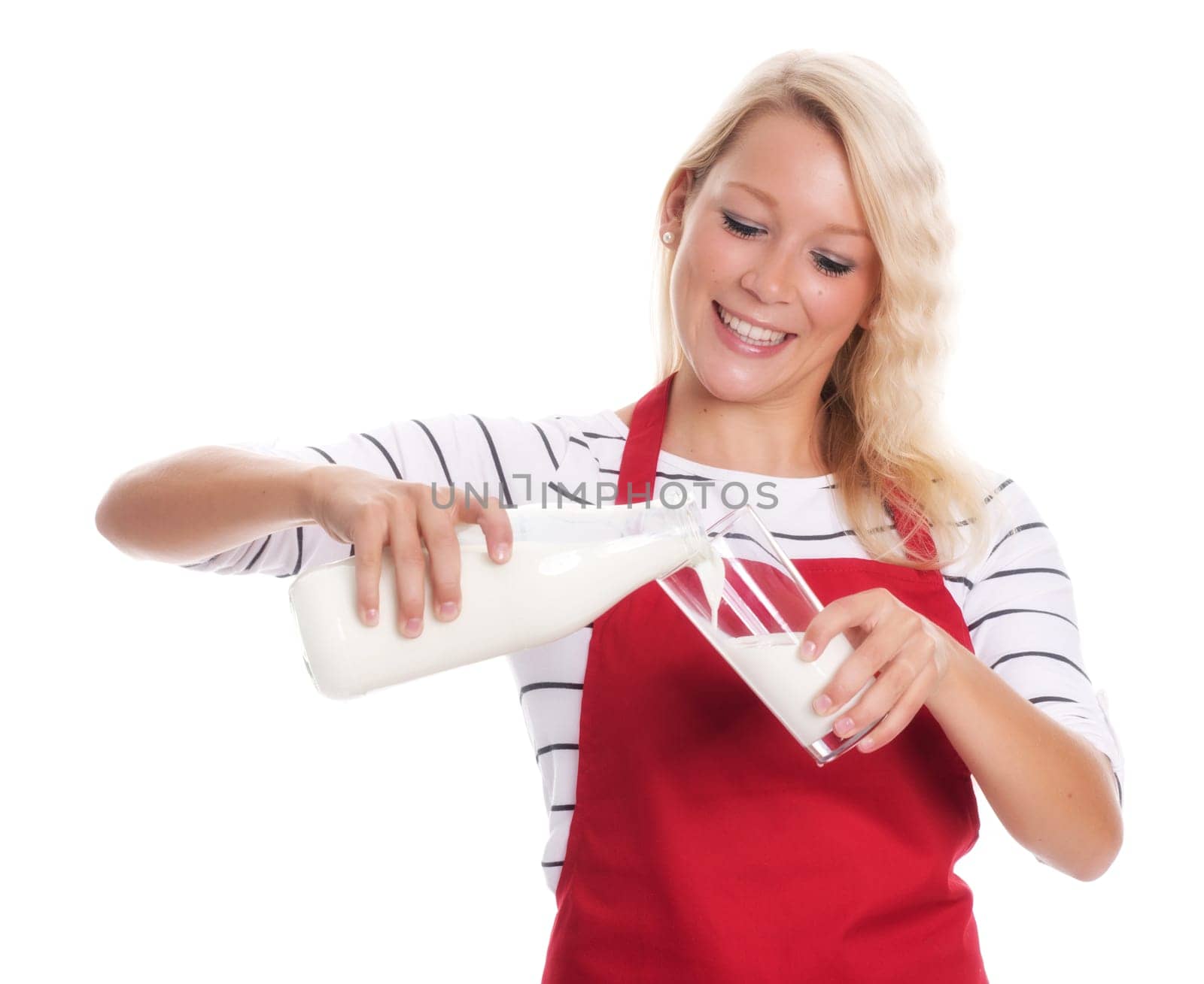 Housewife in apron pours whole milk into a glass