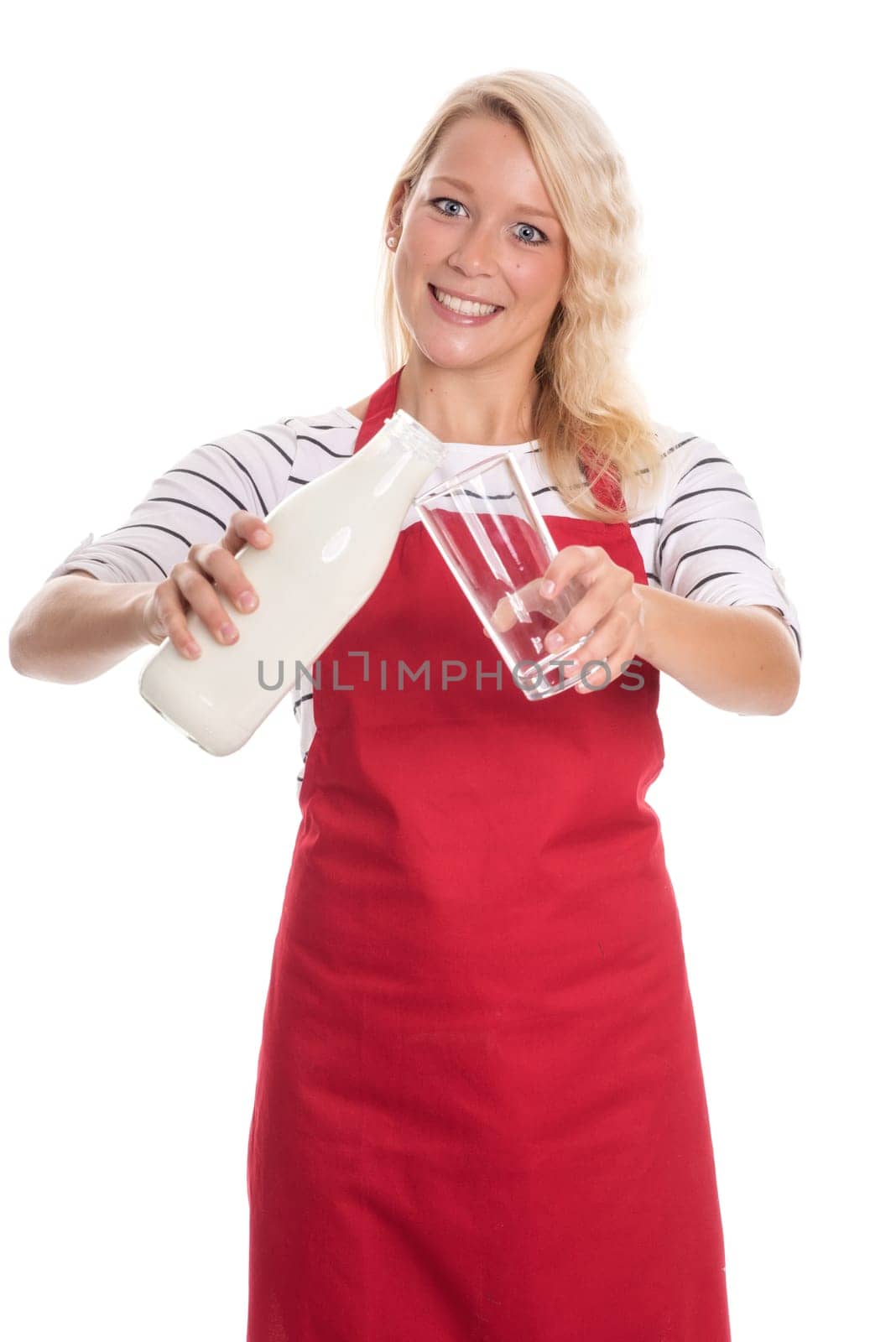 Woman in kitchen apron holds a bottle of fresh milk and a glass