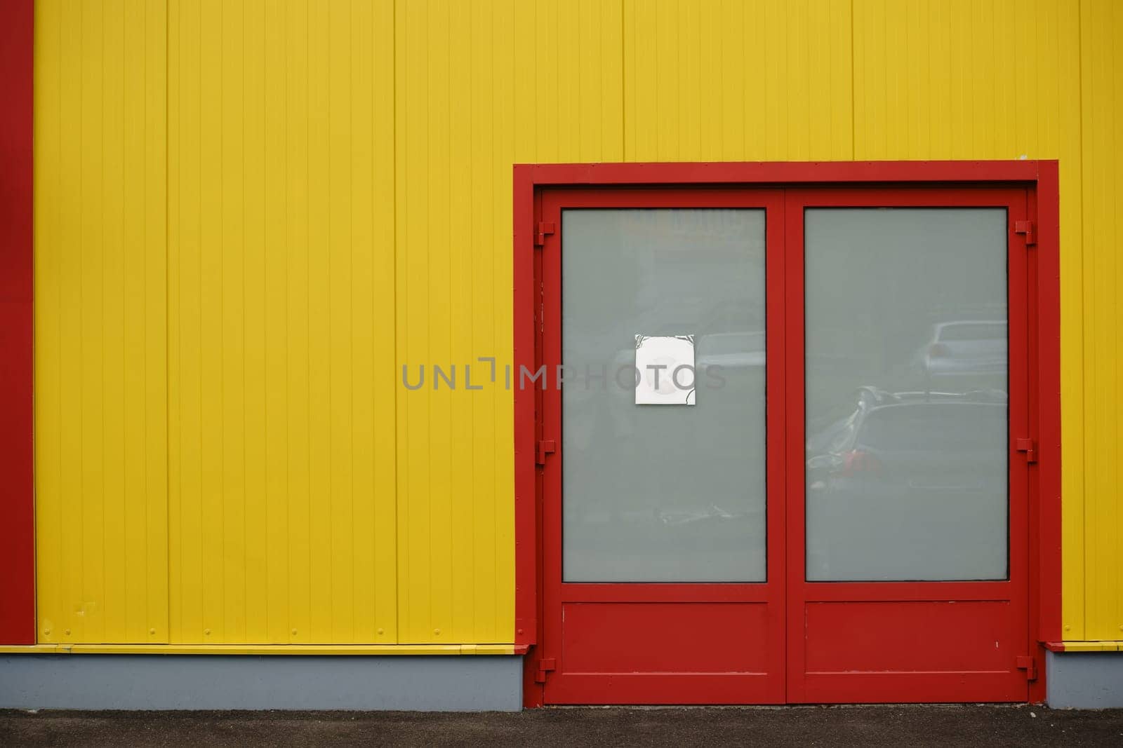 A colourful and distinctive side wall of a shopping centre with a side entrance and a bright colour.