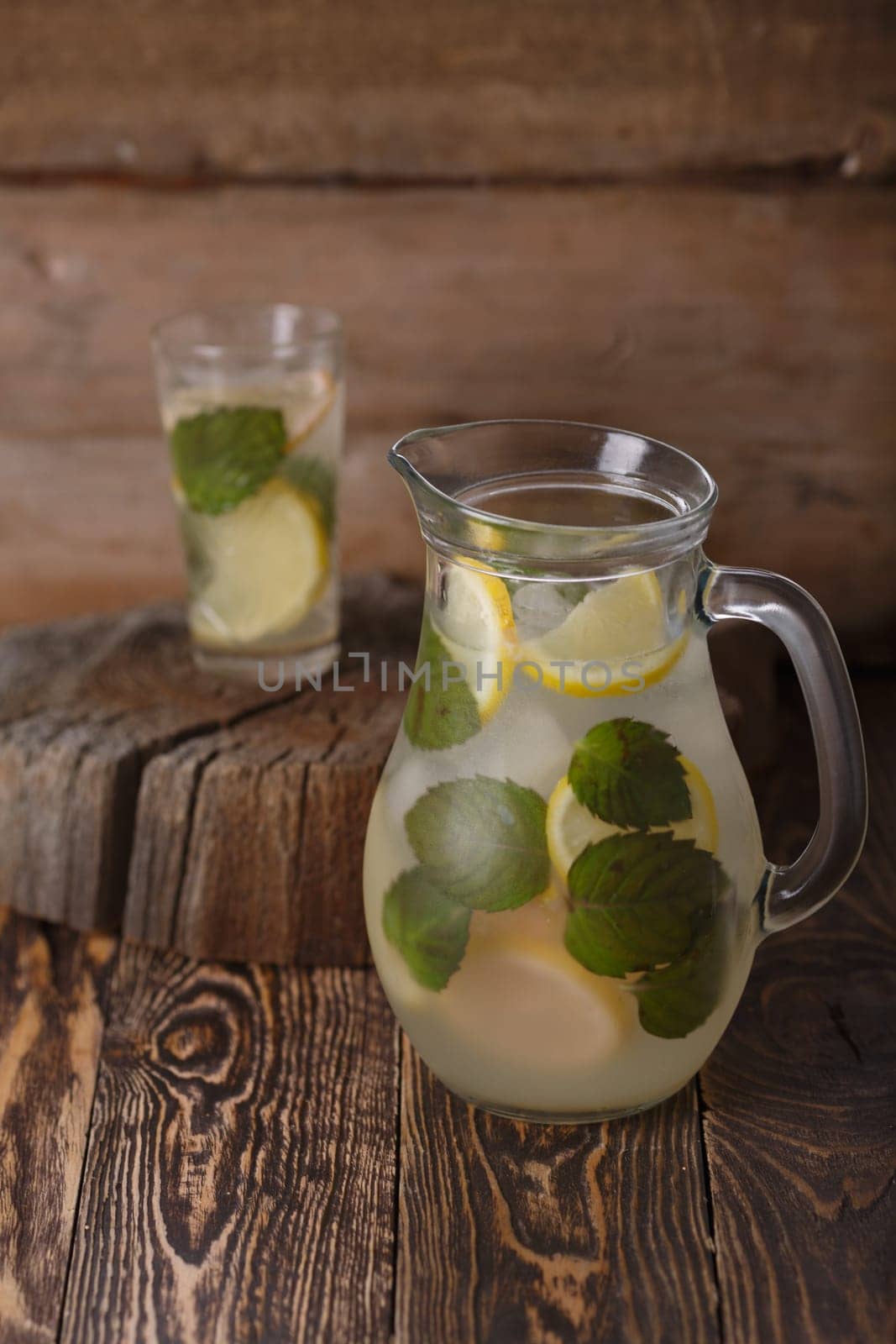Pitcher of mint lemonade on a wooden table near yellow wild flowers