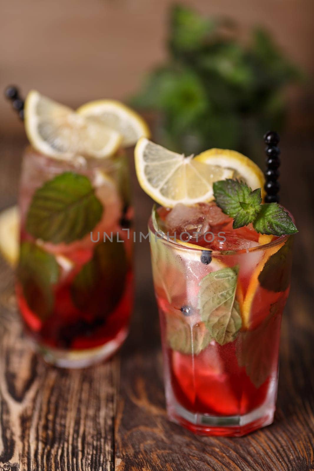 Two glasses of blueberry mojito cocktail on a wooden table