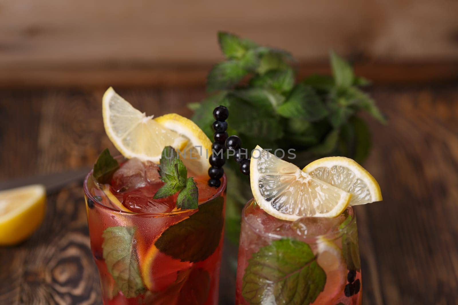 Two glasses of blueberry mojito cocktail on a wooden table