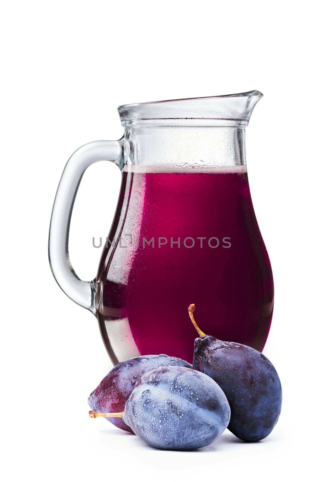 Fresh plum juice in a pitcher. Full jug of plum drink with plums on foreground