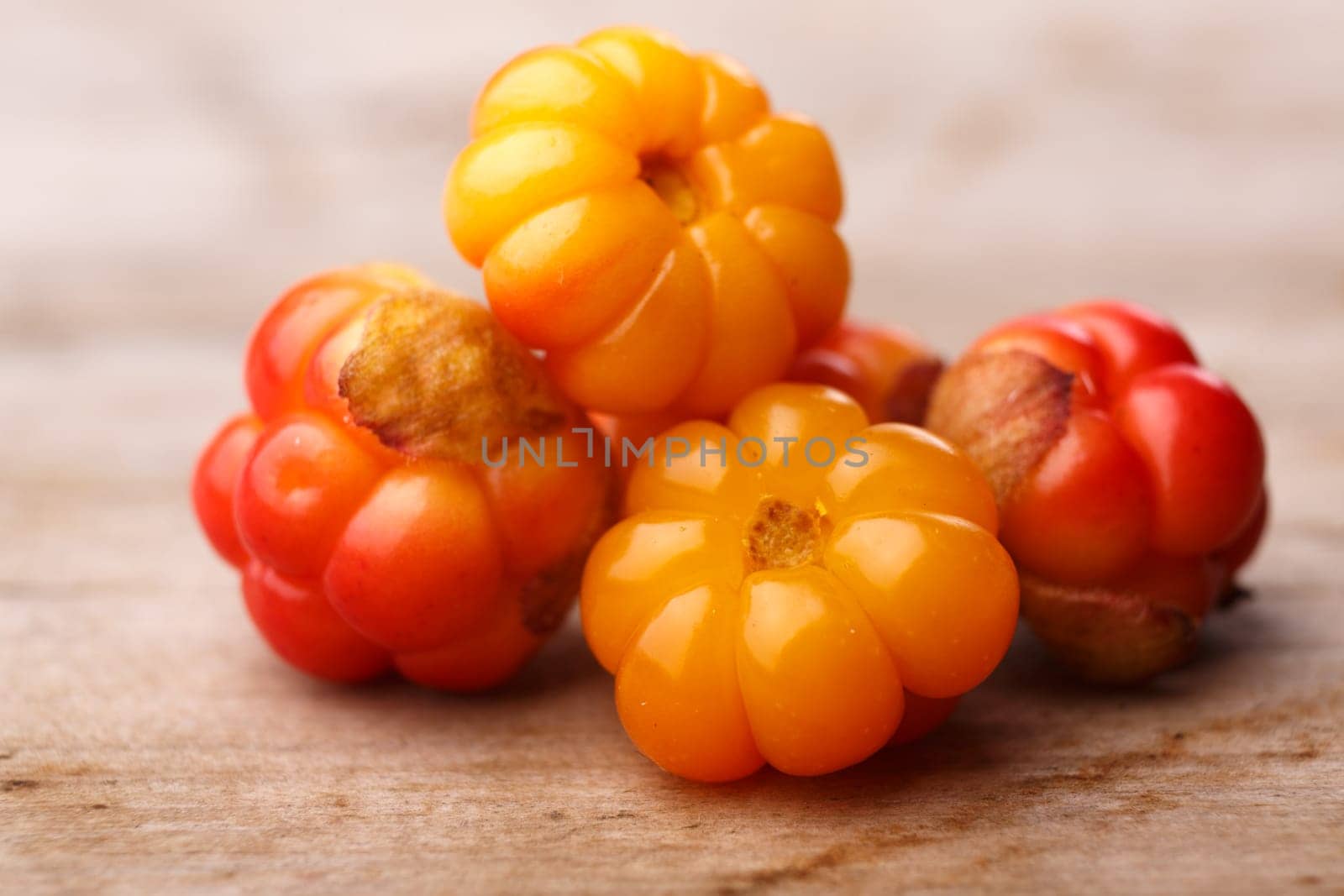 Cloudberries (moroshka) on a wooden table. Wild northern berry. Shallow depth of field