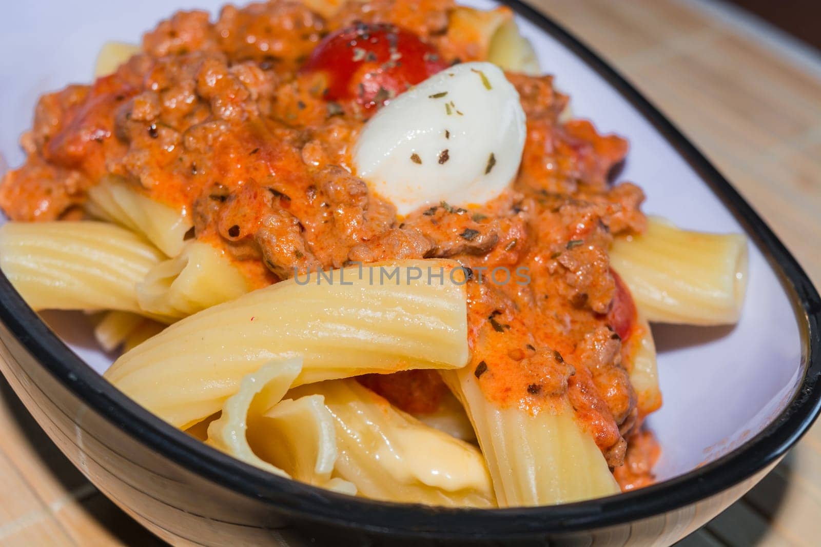 Rigatoni noodles with Bolognese sauce in a bowl.