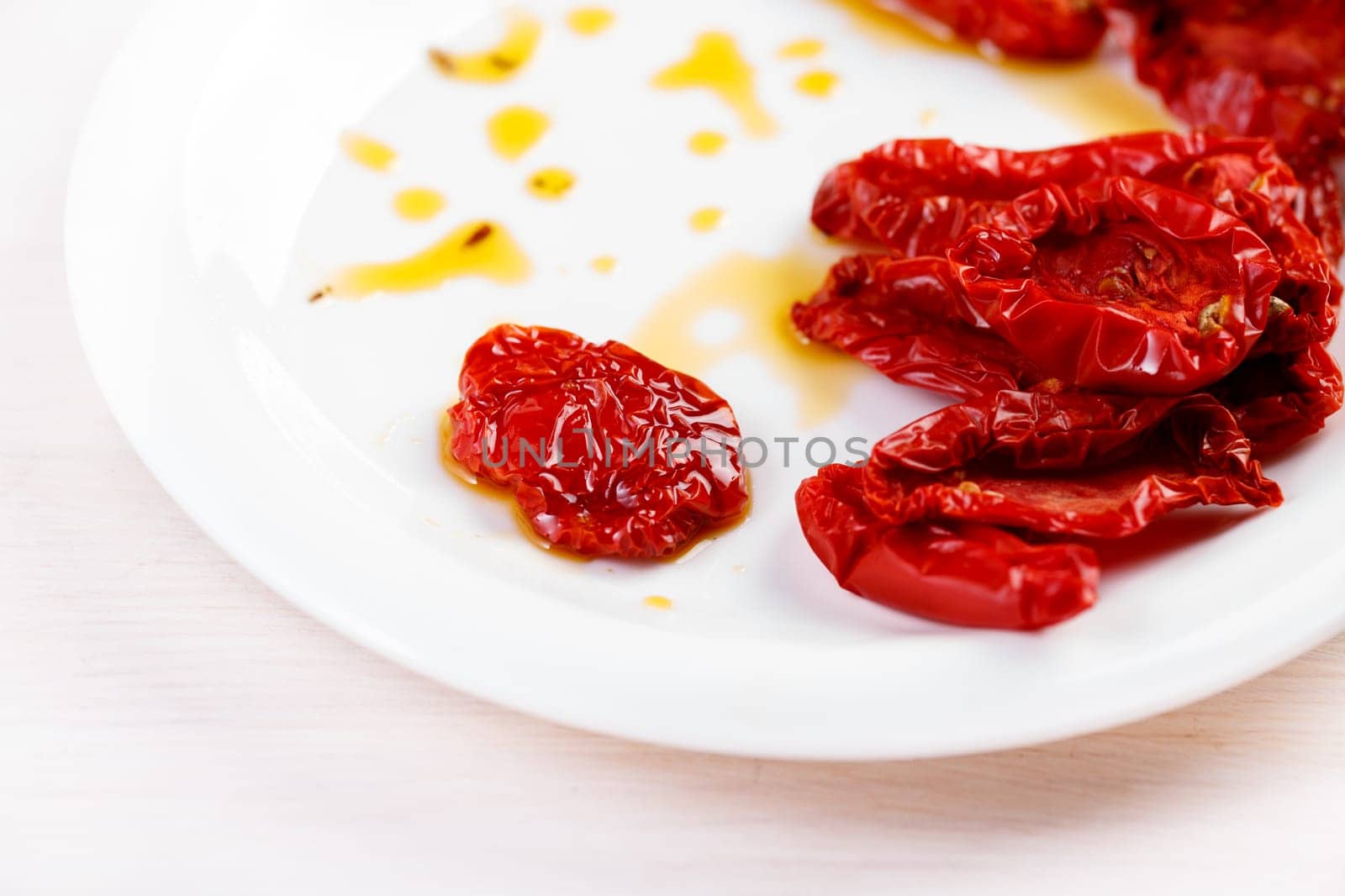 Sun dried tomatoes with olive oil on white plate