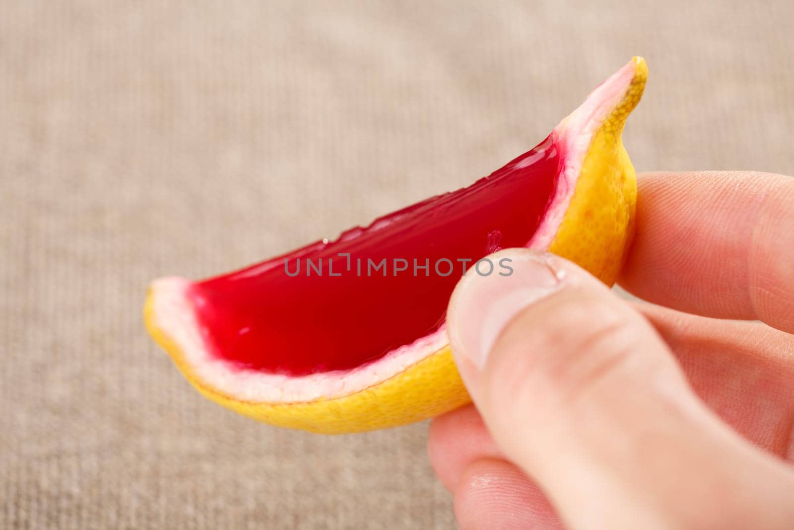 Male hand holding a lemon tequila strawberry jelly (jello) shot. Selective focus on a shooter