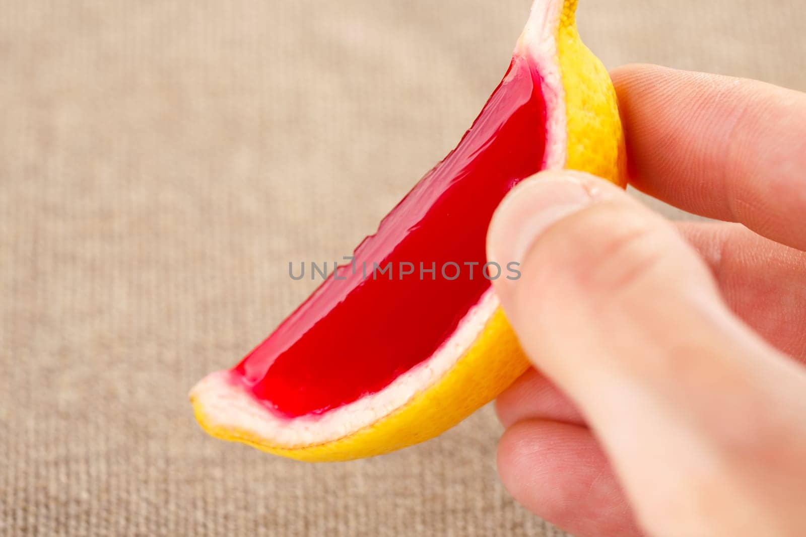 Male hand holding a lemon tequila strawberry jelly (jello) shot. Selective focus on a shooter