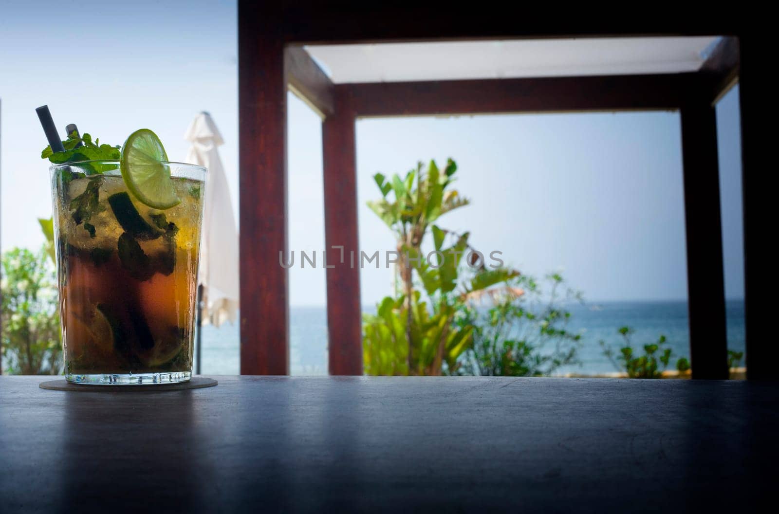 Mojito drink on wood bar with lounger bed and blur beach background