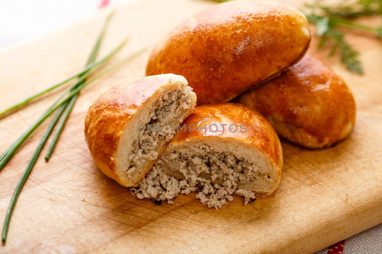 Russian pirozhki (baked patties) on wooden cutboard