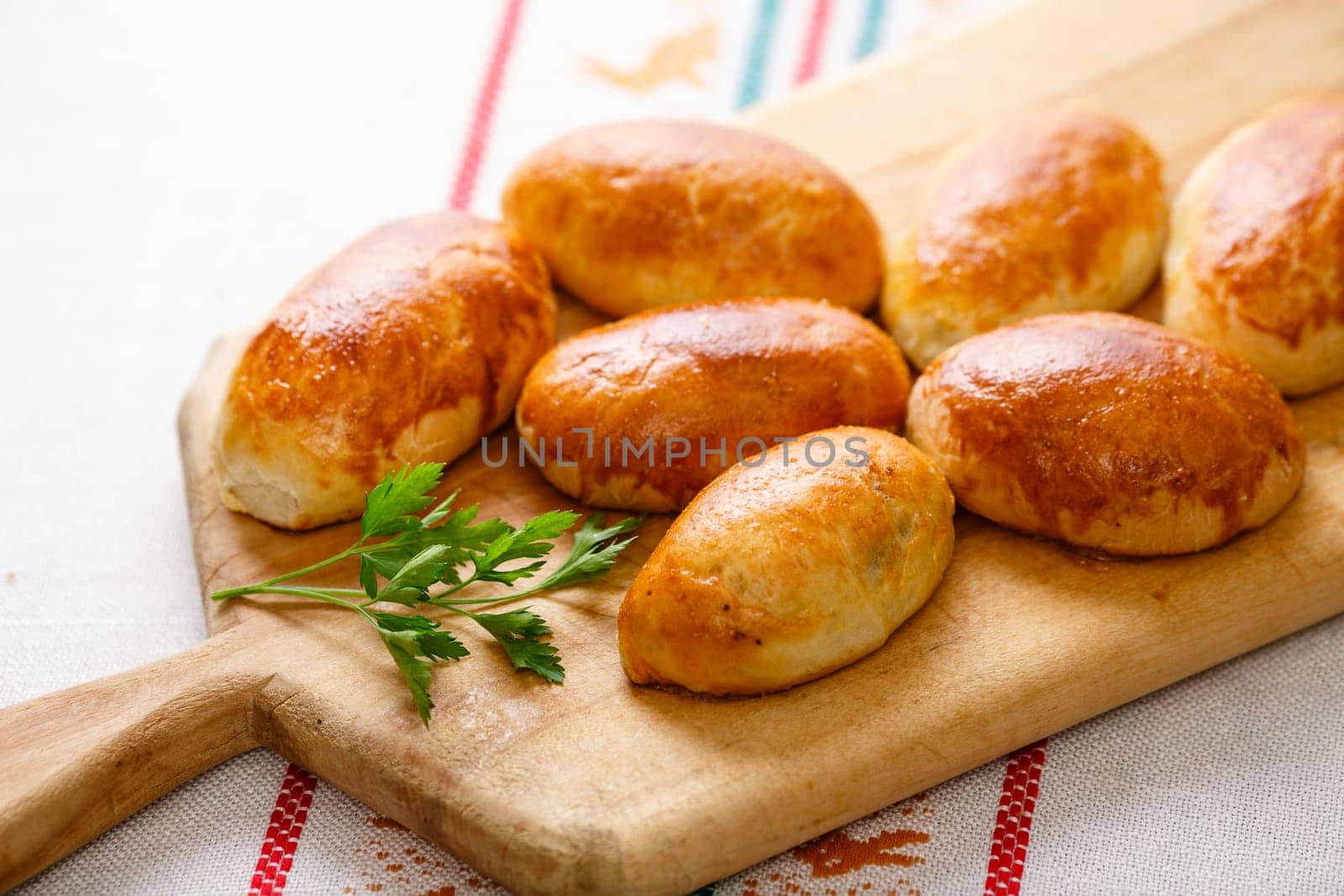 Russian pirozhki (baked patties) on wooden cutboard
