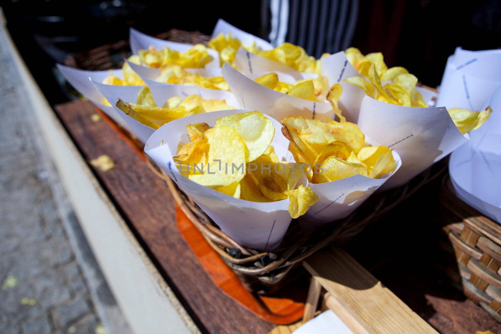 Fried potato chips  in paper cornets for sell at market stall on wicker basket